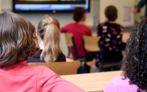 the back of two girls in a. class looking ahead