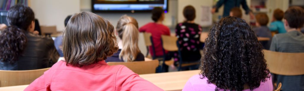 the back of two girls in a. class looking ahead