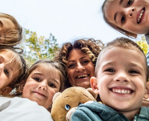Women and children smiling and looking down at the camera for a pose