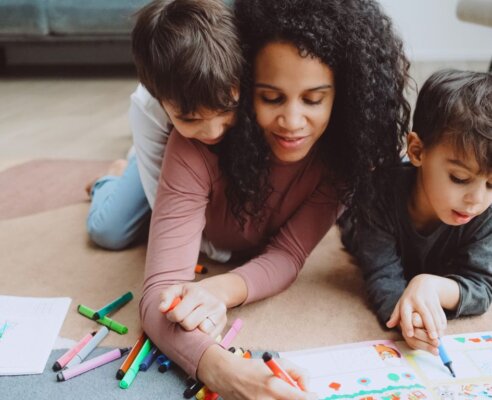 mother and two boys colouring on the ground