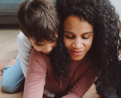 mother and two boys colouring on the ground