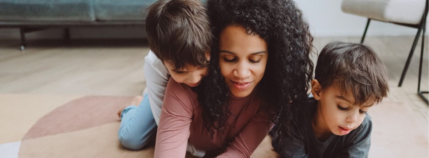 mother and two boys colouring on the ground