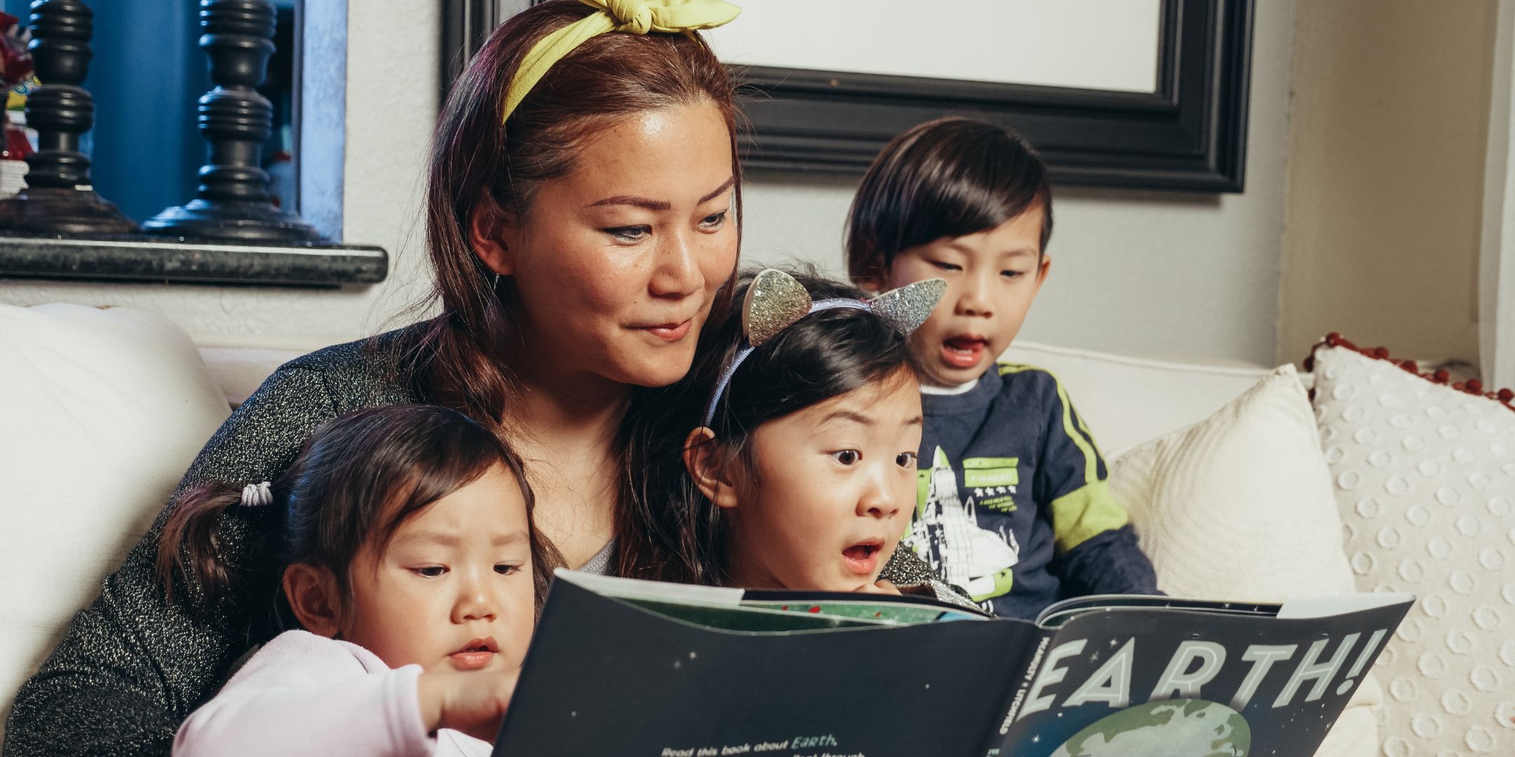 Mom with three kids on lap reading a book