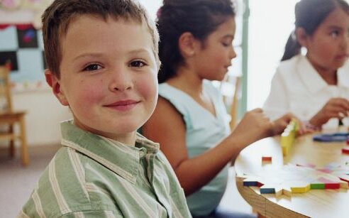 boy in classroom smiling at camera
