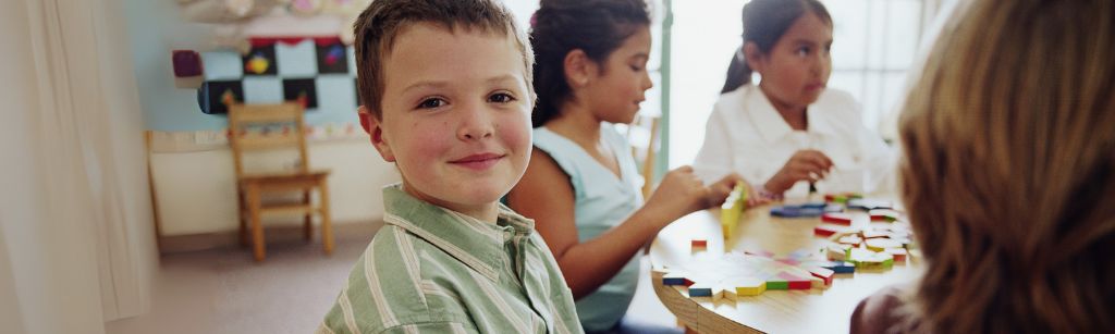 boy in classroom smiling at camera