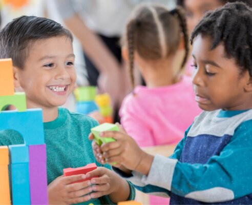 Two boys smiling and playing with blocks