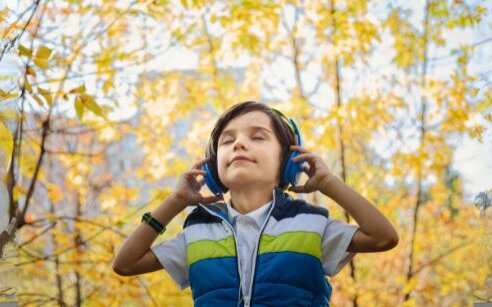 kid in forest with eyes closed and headphones on