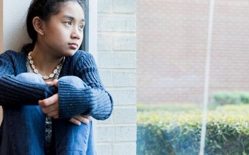 girl looking out window, sad
