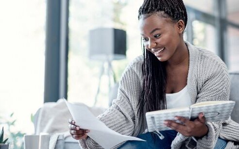 woman on couch with book and organizer writing